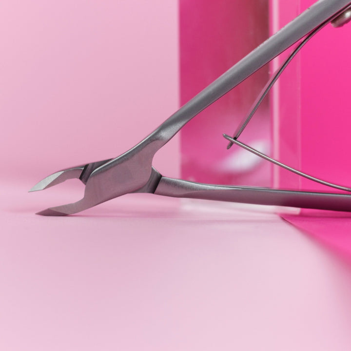 Metal nail clippers on a pink background